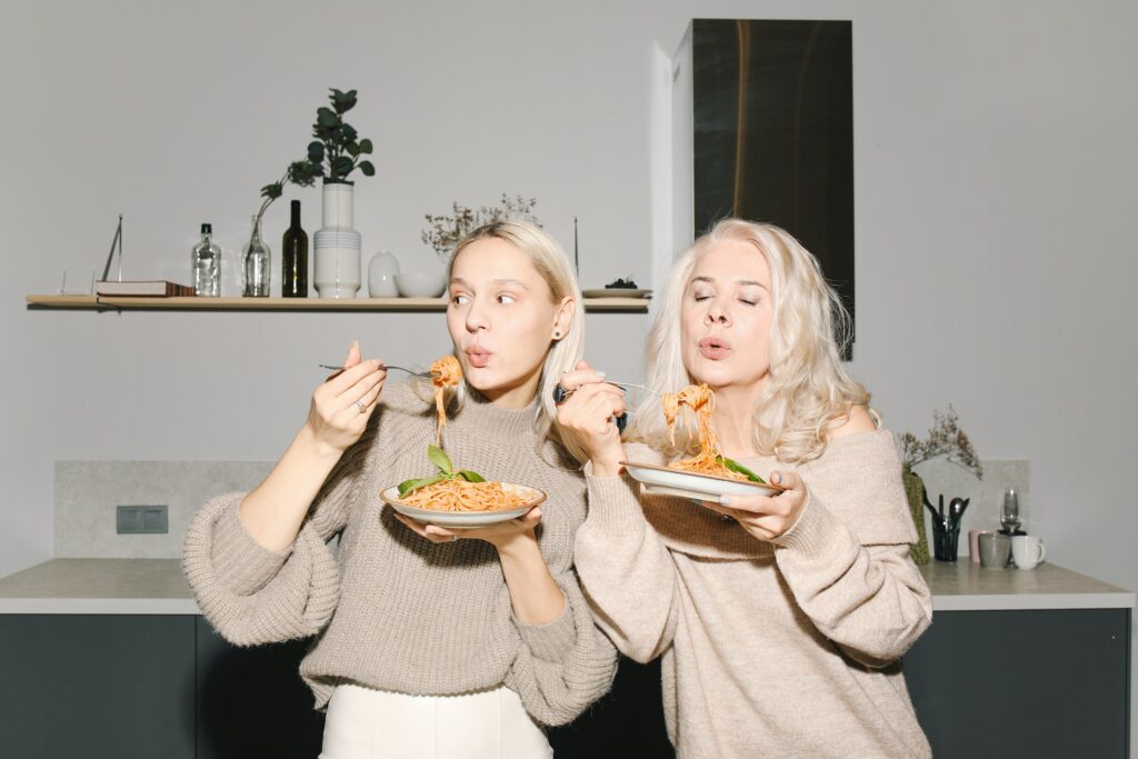Two women eating a bowl of pasta