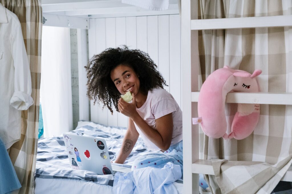 A women eating an apple on a bed.