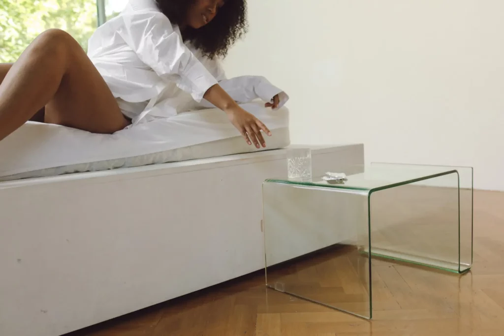 A women reaching for a glass of water from her bed.